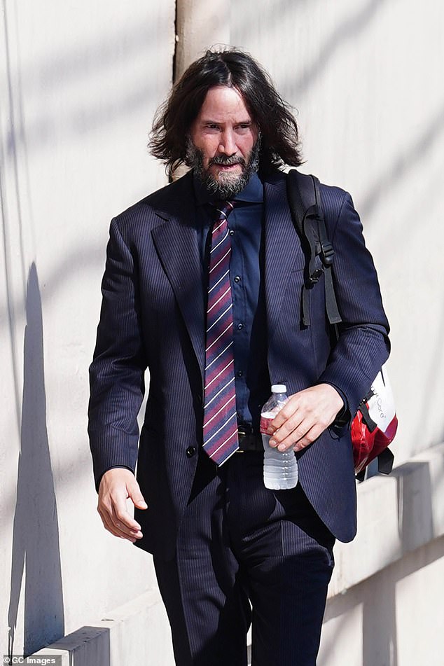 Suited up: His suit featured faint pinstripes, and he paired it with a matching black shirt, a striped red-and-blue tie and comfortable brown boots